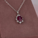 Claw set 18ct white gold pendant with natural ruby gemstone and pear shaped and round brilliant cut diamond halo detail.