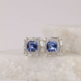 Claw set 18ct white gold stud earrings with natural sapphire gemstone and double diamond halo surround.