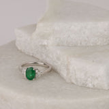 Top view of 18ct white gold ring showcasing the oval natural emerald flanked by tapered baguette diamonds.