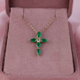 Claw set 18ct yellow gold cross pendant with natural emerald gemstones and round brilliant cut diamond detail.