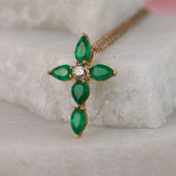 Close up of 18ct yellow gold fancy cross drop pendant featuring 5 natural emeralds (1.41ct total) and a round brilliant cut diamond.