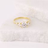 Thea engagement ring featuring round brilliant cut centre diamond yellow gold band.