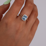 9ct yellow gold blue topaz and diamond halo ring worn on hand showing fresh blue colour and sparkle.