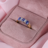 Gold ring with blue sapphire and diamond gemstones in a pink jewellery box.