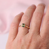 Close-up of emerald cut parti sapphire showing blue and green colour variations in yellow gold engagement ring available at York Jewellers Penrith.