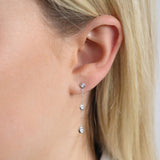 9ct white gold diamond chain drop earrings worn on the ear showing movement and sparkle.