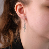 18ct yellow and white gold hoop drop earrings worn on the ear showing arrow-like diamond drop detail and sparkle available at York Jewellers Penrith.