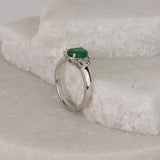 Side profile of 18ct white gold ring showing oval shaped natural emerald and tapered baguette diamond detailing.