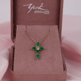 Close-up of 18ct yellow gold cross pendant showcasing 1.41ct total natural emeralds and 0.29ct round brilliant cut diamond available at York Jewellers Penrith.