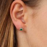 9K yellow gold emerald and diamond halo stud earrings worn on the ear showing the green centre and diamond sparkle, available at York Jewellers Penrith. 