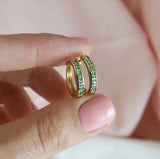 Close-up of 9ct yellow gold huggie hoop earrings showcasing emerald and diamond detail, available at York Jewellers Penrith.