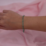 18ct white gold emerald and diamond tennis bracelet worn on the wrist showing rich green colour and sparkle.