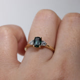 Close-up of 18ct yellow gold trilogy ring showcasing a certified cushion cut natural Australian teal sapphire, available at York Jewellers Penrith.