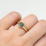 9ct yellow gold Ingrid Round Ring worn on hand showing shifting blue-green teal sapphire colour.
