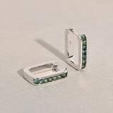 9ct white gold Jules Huggie Earrings showing the princess cut teal sapphires set closely along the hoop.