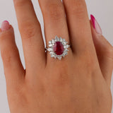 18ct white gold ruby flower style ring worn on hand showing rich red oval gemstone and diamond petal detail.