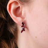 18ct white gold ruby leaf style drop earrings worn on the ear showing rich red gemstones and diamond detailing.