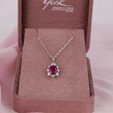 Close-up of 18ct white gold pendant showcasing 2.01ct natural oval shaped ruby and surrounding diamond halo available at York Jewellers Penrith.