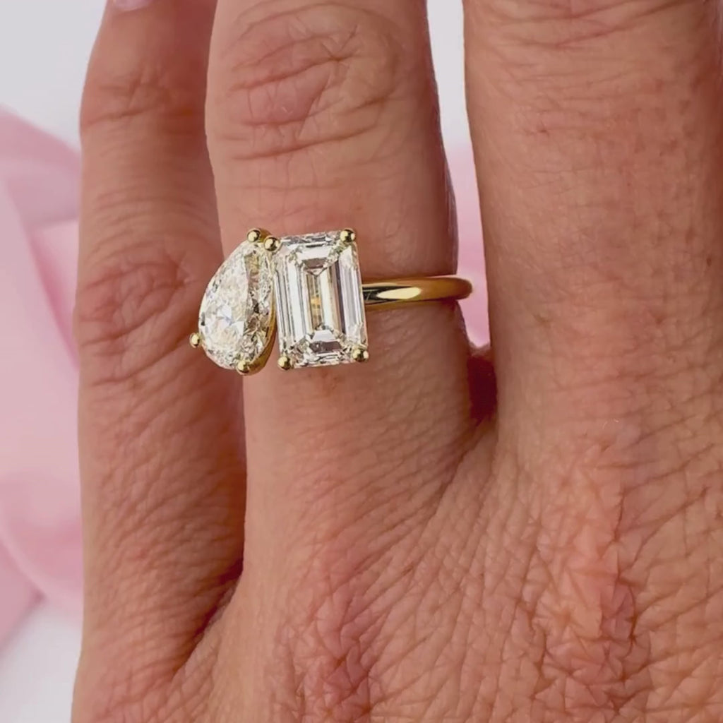 Pear shape and emerald cut diamond engagement ring on hand yellow gold Sydney.