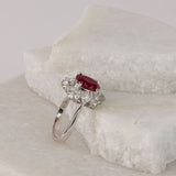 Side profile of 18ct white gold halo flower style ring showing natural oval ruby and layered diamond detailing.