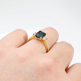 18ct yellow gold Valerie Ring worn on hand showing the trilogy design and shifting teal sapphire colour.